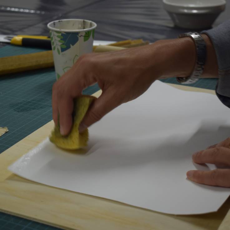 Eine Hand tupft ein Blatt Papier mit einem nassen Schwamm ab